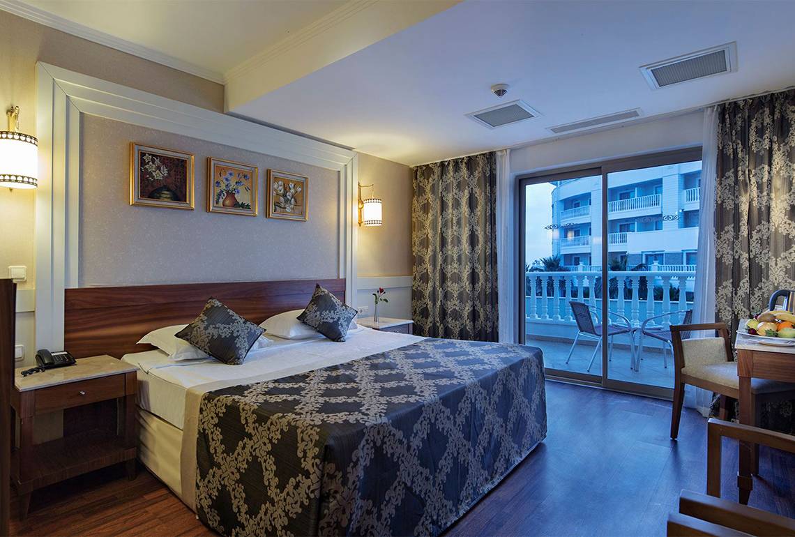 Hotelzimmer im Alba Queen Hotel mit Doppelbett, Balkon und Blick auf ein Gebäude.