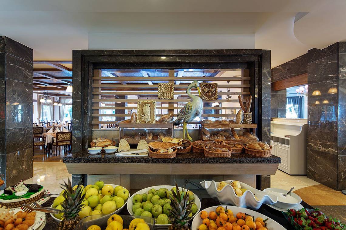 Buffet-Tisch im Alba Queen Hotel mit verschiedenen Broten, Obst und Desserts.