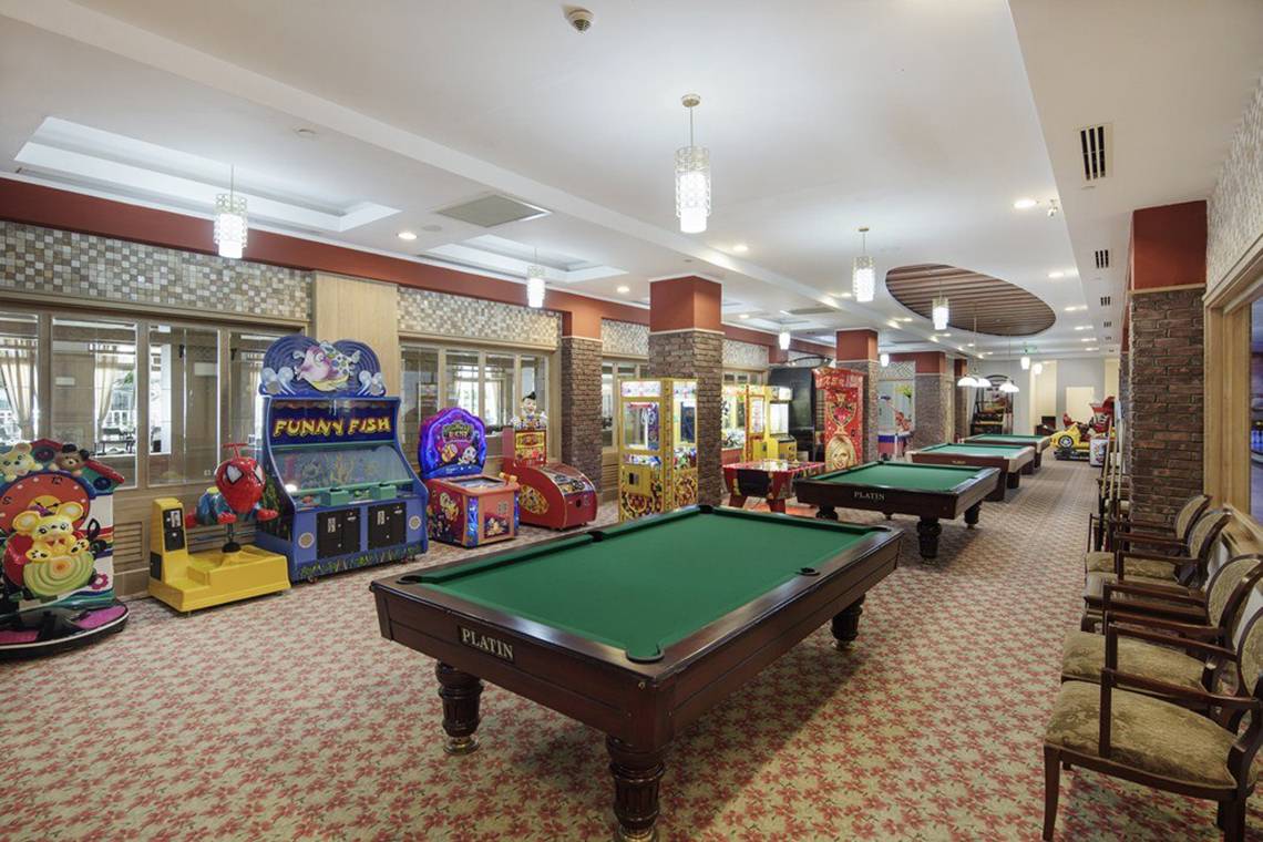 Spielzimmer im Hotel Alba Queen mit Billardtischen, Spielkonsolen und Sitzgelegenheiten.