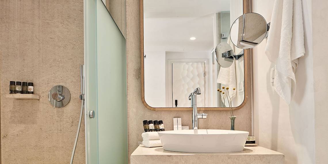 Badezimmer im Myconian Kyma Hotel mit Dusche, Waschbecken und Spiegel.