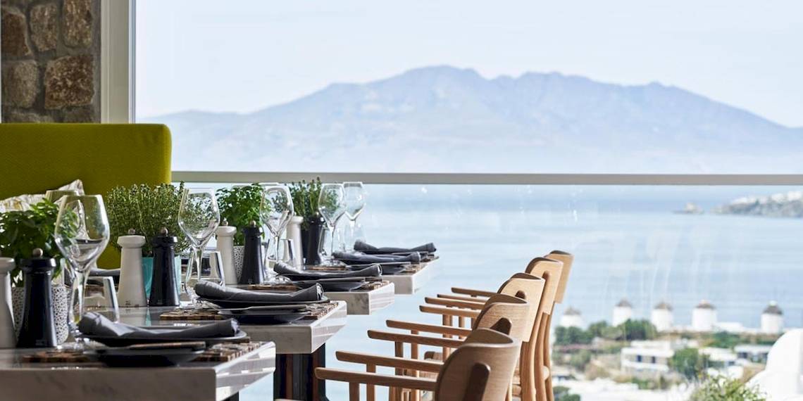 Myconian Kyma Hotel Innenbereich mit Tisch und Meerblick.