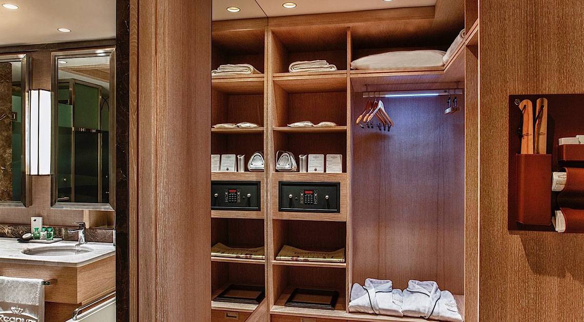 Innenansicht eines Kleiderschranks im Regnum Carya Golf & Spa Resort mit Regalen, Safe und Accessoires.