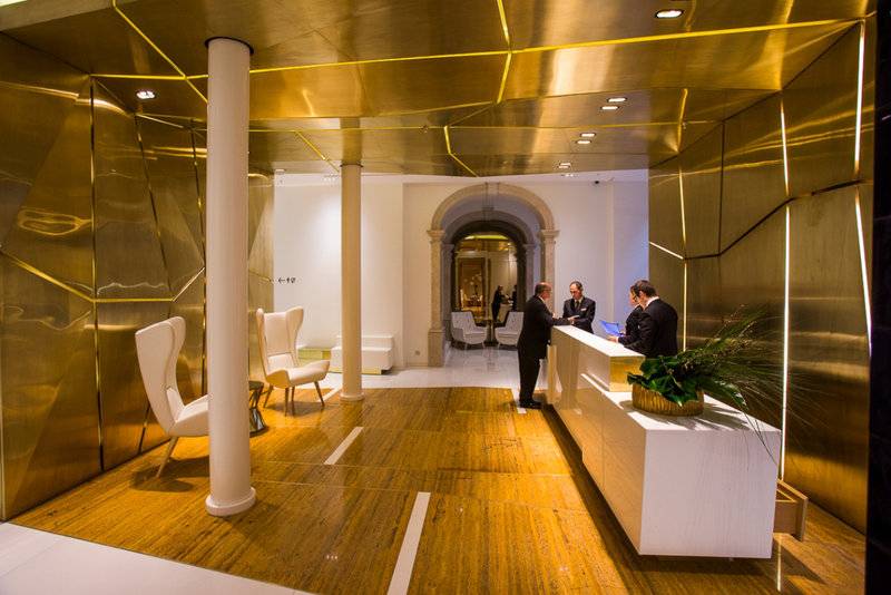 Empfangsbereich des Portugal Boutique Hotels mit goldenen Wänden und Holzboden.