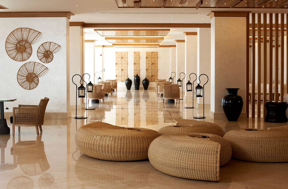 Lobby des Mitsis Blue Domes Resort & Spa mit braunen Möbeln und schwarzen Vasen.