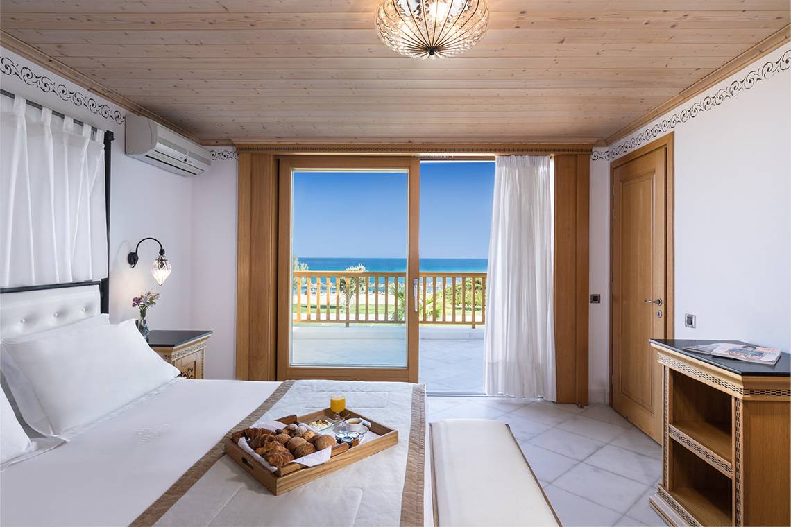 Zimmer im Mitsis Blue Domes Resort & Spa mit Frühstückstablett und Meerblick.