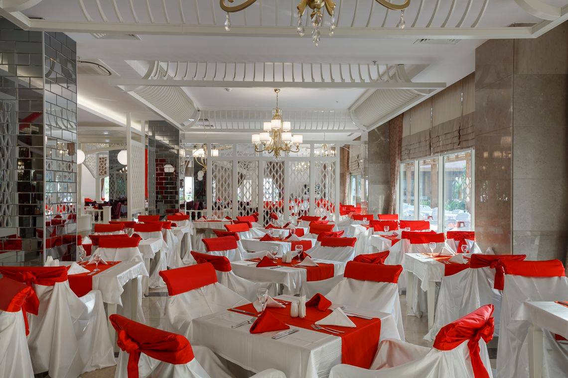 Innenbereich des Well Palace Side Hotels mit vielen weiß und rot gedeckten Tischen.