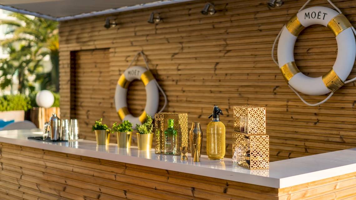 Barbereich im Iberostar Selection Playa de Palma Hotel mit holzverkleideten Wänden, goldenen Dekorationen und einer Flasche Moet.