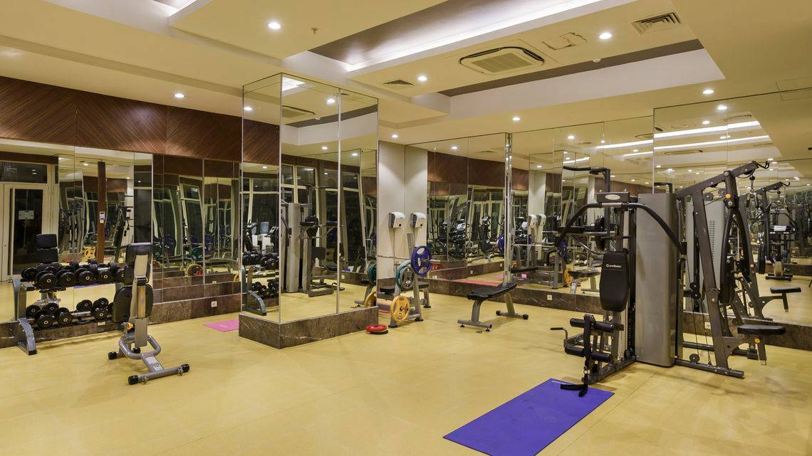 Fitnesscenter im Well Palace Side Hotel mit vielen Geräten und Spiegeln.