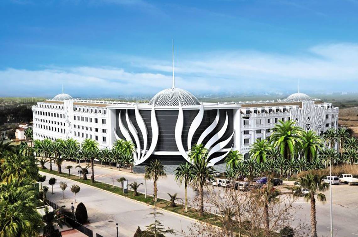 Außenansicht des Defne Defnem Hotels mit moderner Architektur und palmenbestandener Einfahrt.