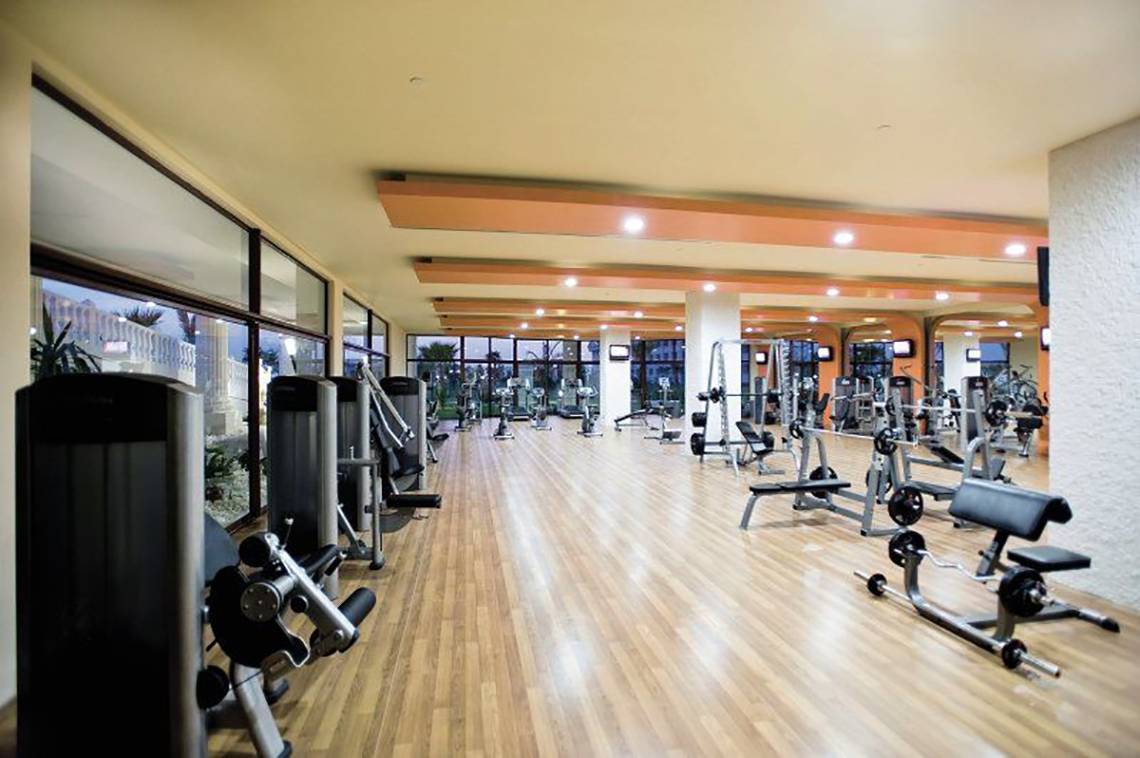 Fitnessstudio im Defne Defnem Hotel mit vielen Geräten und großen Fenstern.