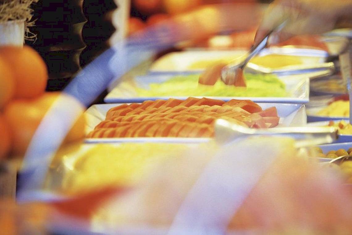 Buffet-Tisch mit verschiedenen Obstsorten und Lebensmitteln, teilweise in weißen Tellern.