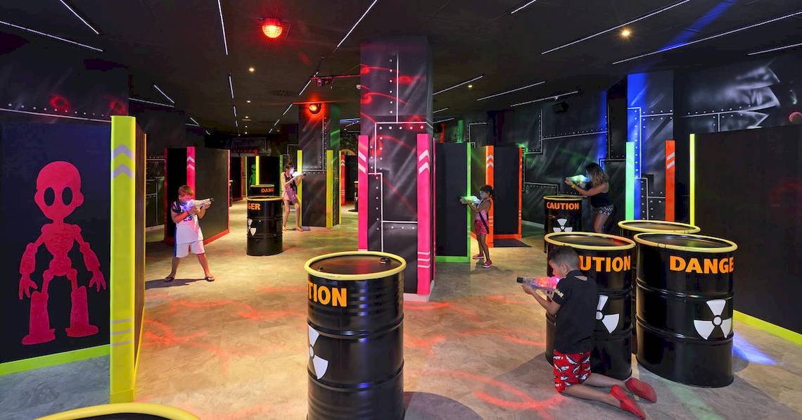 Kinder spielen Laser Tag in einem farbenfrohen Spielbereich des Sol Principe Hotels.