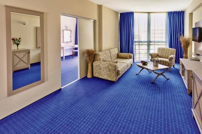 Wohnbereich im DAS Club Hotel Sunny Beach mit blauem Teppich und modernen Möbeln.