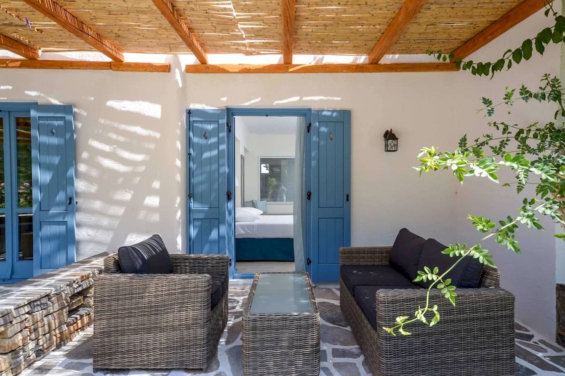 Terrasse des Alkyoni Beach Hotels mit zwei Sofas, einem Tisch und Blick auf das Schlafzimmer.
