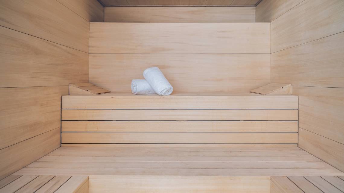 Innenansicht der Sauna im Hotel Iberostar Selection Sabila mit leeren Holzbänken und zwei weißen Handtüchern.