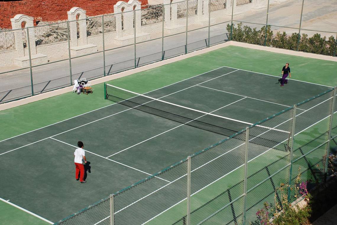 Tennisplatz im Pyramisa Beach Resort Sahl Hasheesh mit zwei Spielern und einem Netz.