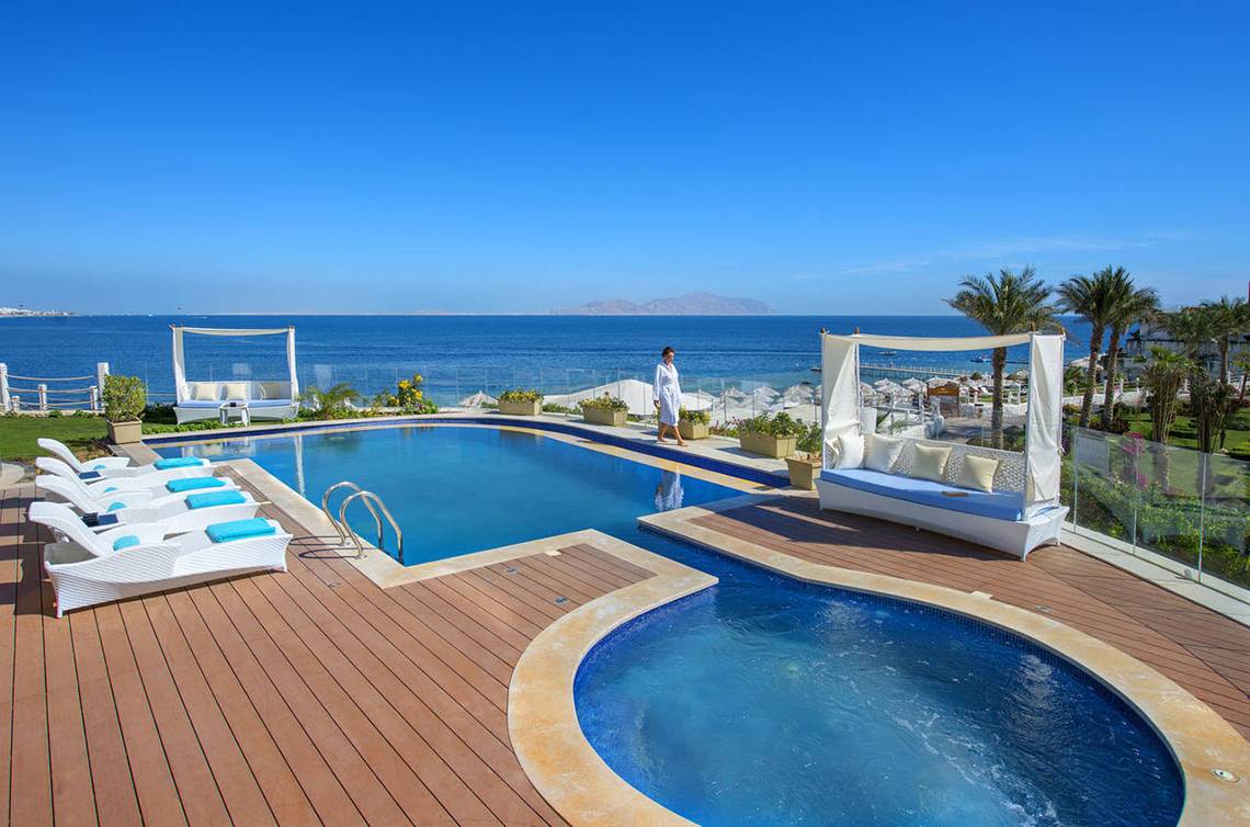 Außenpoolbereich des Sunrise Arabian Beach Resorts mit Loungeliegen und Blick auf das Meer.