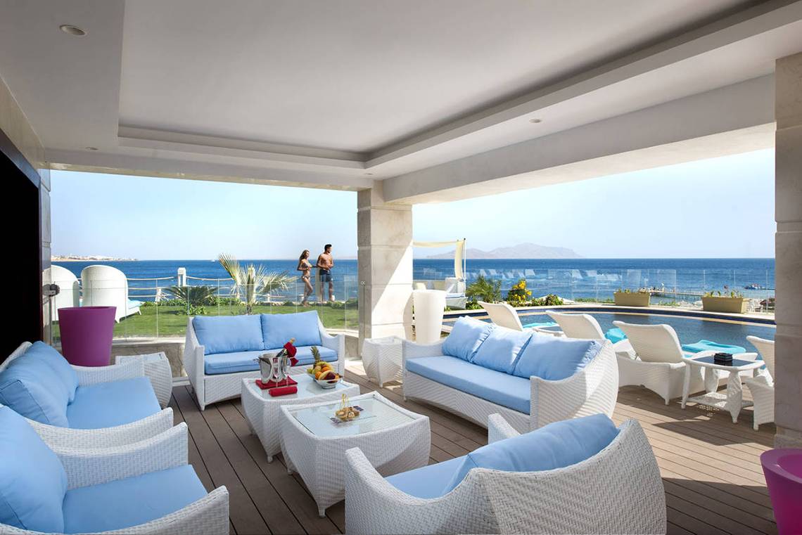 Terrasse mit Meerblick im Sunrise Arabian Beach Resort mit weißen Möbeln und zwei Personen, die den Ausblick genießen.