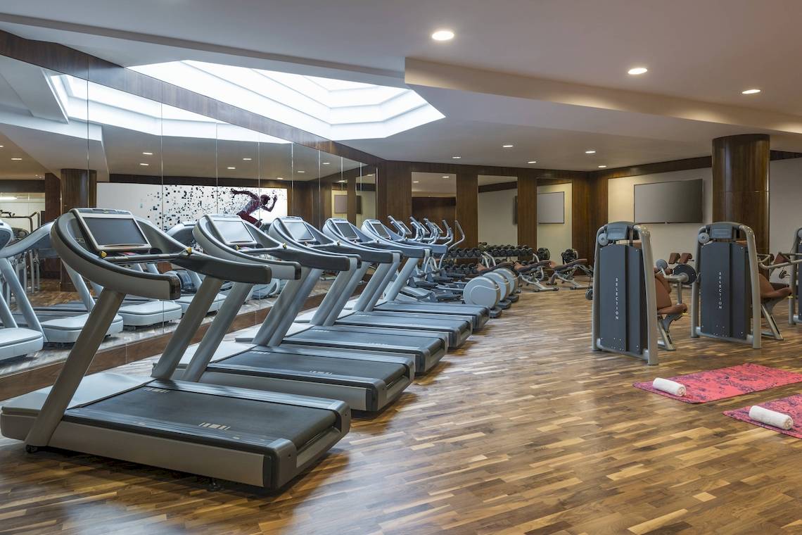 Fitnessstudio im Sheraton Oman Hotel mit einer Reihe von Laufbändern und Trainingsgeräten.