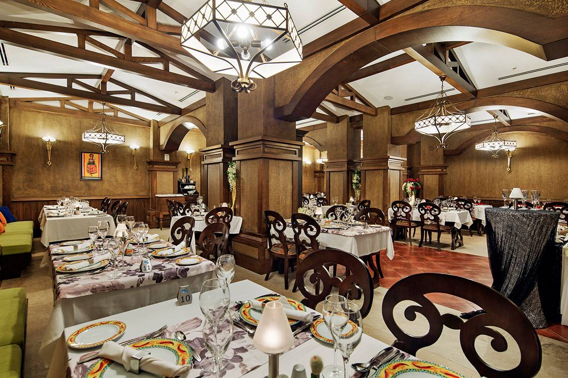 Innenbereich eines Restaurants im Crystal Waterworld Aqua Collection Hotel mit gedeckten Tischen und Holzarchitektur.