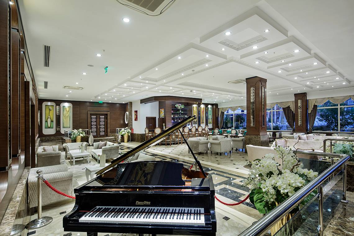 Hotellobby des Crystal Waterworld Aqua Collection mit Klavier, Sofas und Blumenvase.