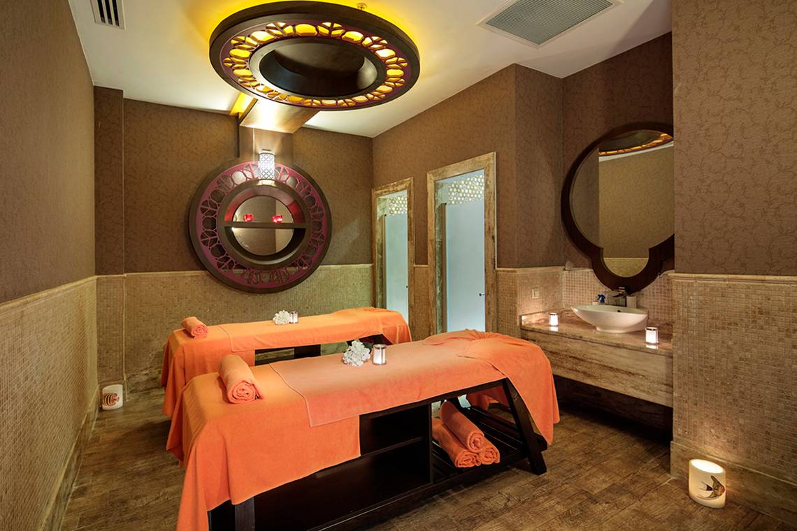Spa-Behandlungsraum im Crystal Waterworld Aqua Collection mit zwei Massagetischen und einem Waschbecken.