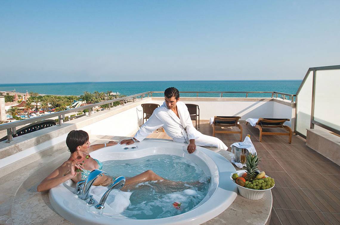 Ein Paar genießt ein Whirlpool-Erlebnis auf der Dachterrasse des Crystal Waterworld Aqua Collection Hotels mit Blick auf das Meer.