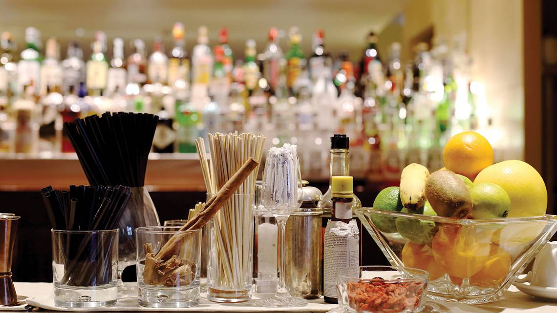 Cocktail-Zutaten auf einer Bar in einem Hotel, mit verschiedenen Früchten und Flaschen im Hintergrund.