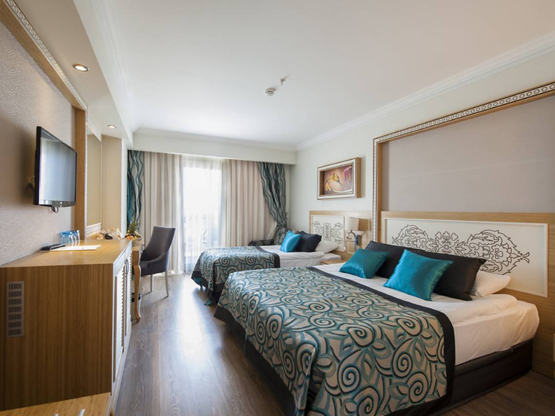 Innenansicht eines Doppelzimmers im Crystal Waterworld Aqua Collection Hotel mit zwei Betten, Fernseher, und Wohnzimmerbereich.