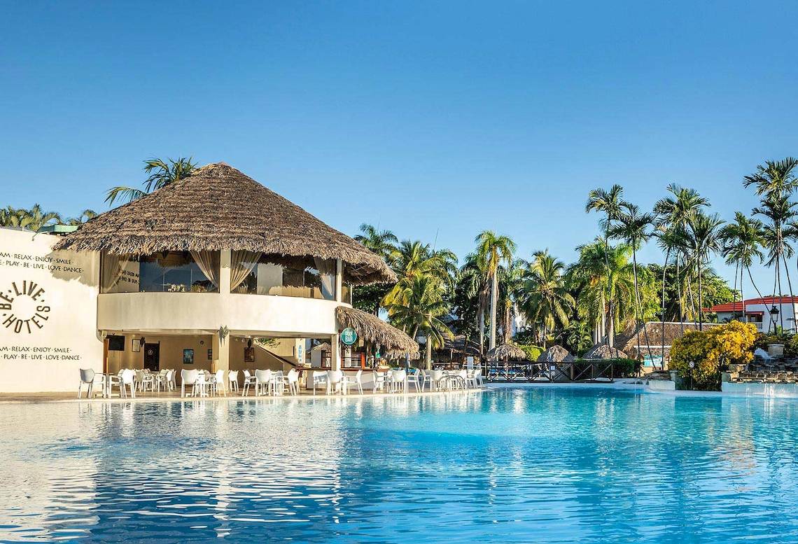 Außenansicht des Marien Puerto Plata Hotels mit Pool, Bar und Sonnenschirmen.