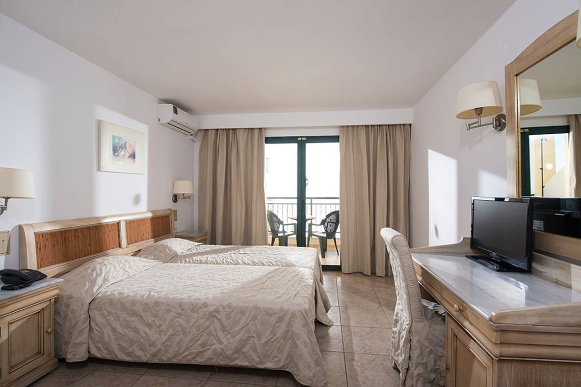 Doppelzimmer mit Balkon im Gouves Water Park Holiday Resort, inklusive zwei Betten und einem Schreibtisch.