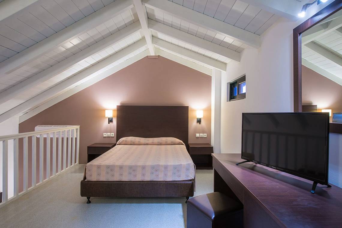Schlafzimmer im Gouves Water Park Holiday Resort mit Dachschrägen, Bett, Fernseher und Nachttischen