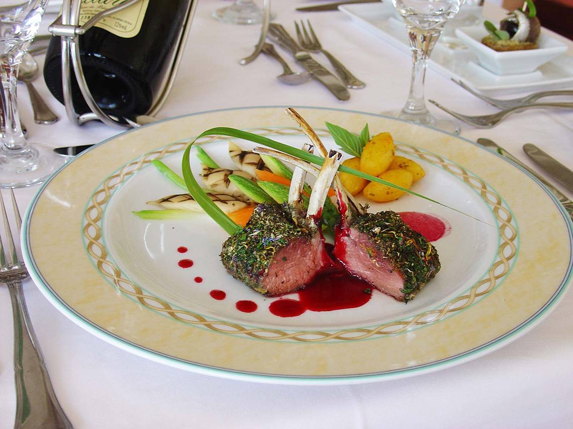 Ein gegrilltes Lammkarree mit Kräutern auf einem dekorativ bedruckten Teller im Rodos Palladium Hotel.