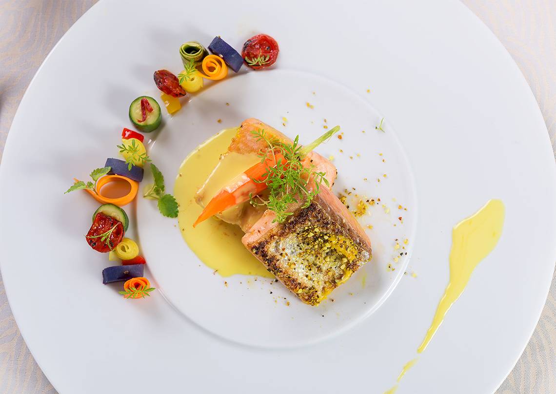 Gegarter Lachs auf weißem Teller mit Gemüse und Sauce