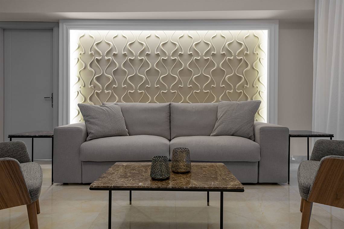 Wohnzimmer mit grauer Couch, marmorfarbenem Tisch und gemusterter Wand