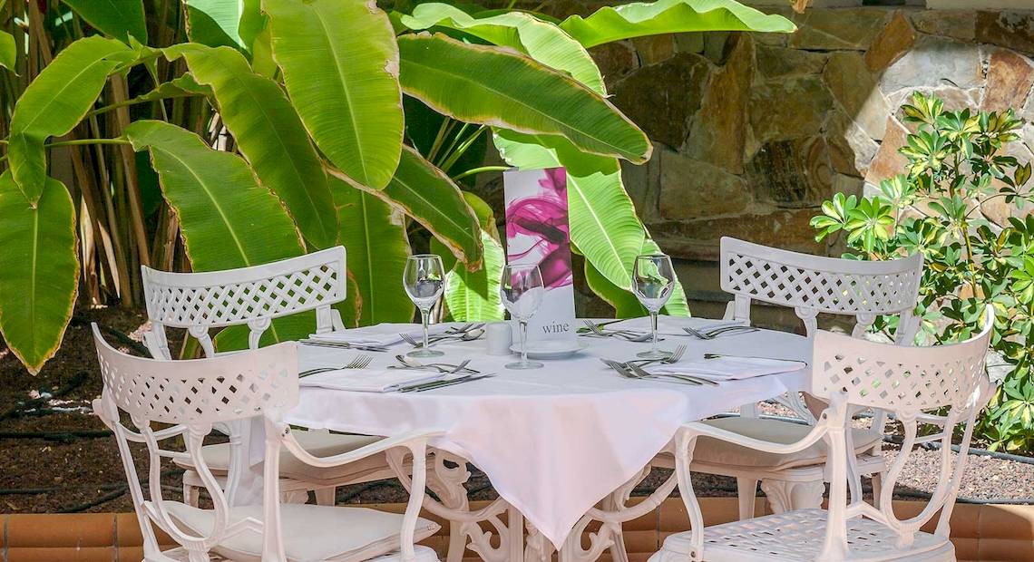 Außentisch im Barcelo Corralejo Bay Hotelgarten mit gedecktem Tisch und Weinglas