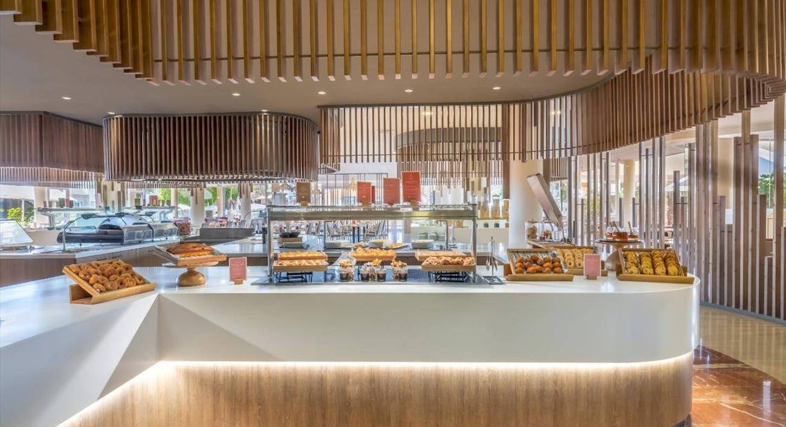 Frühstücksbuffet im Barcelo Corralejo Bay Hotel mit verschiedenen Gebäcksorten und Holzelementen.