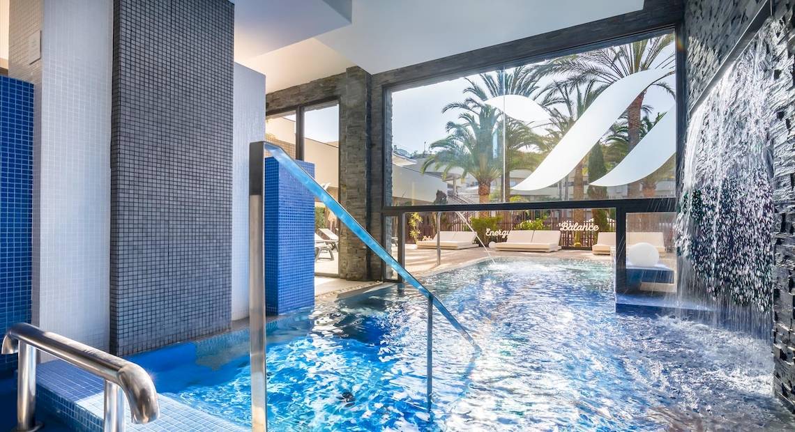 Innenpool im Barcelo Corralejo Bay Hotel mit blauen Fliesen und Wasserfall.
