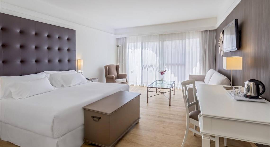 Hotelzimmer im Barcelo Corralejo Bay mit Doppelbett, Wohnzimmerecke und Fernseher an der Wand
