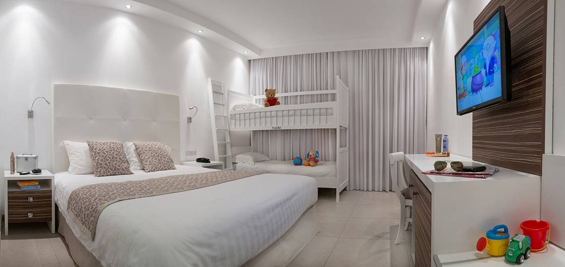 Doppelzimmer im Asterias Beach Hotel mit zwei Betten, Fernseher und Spielzeug.