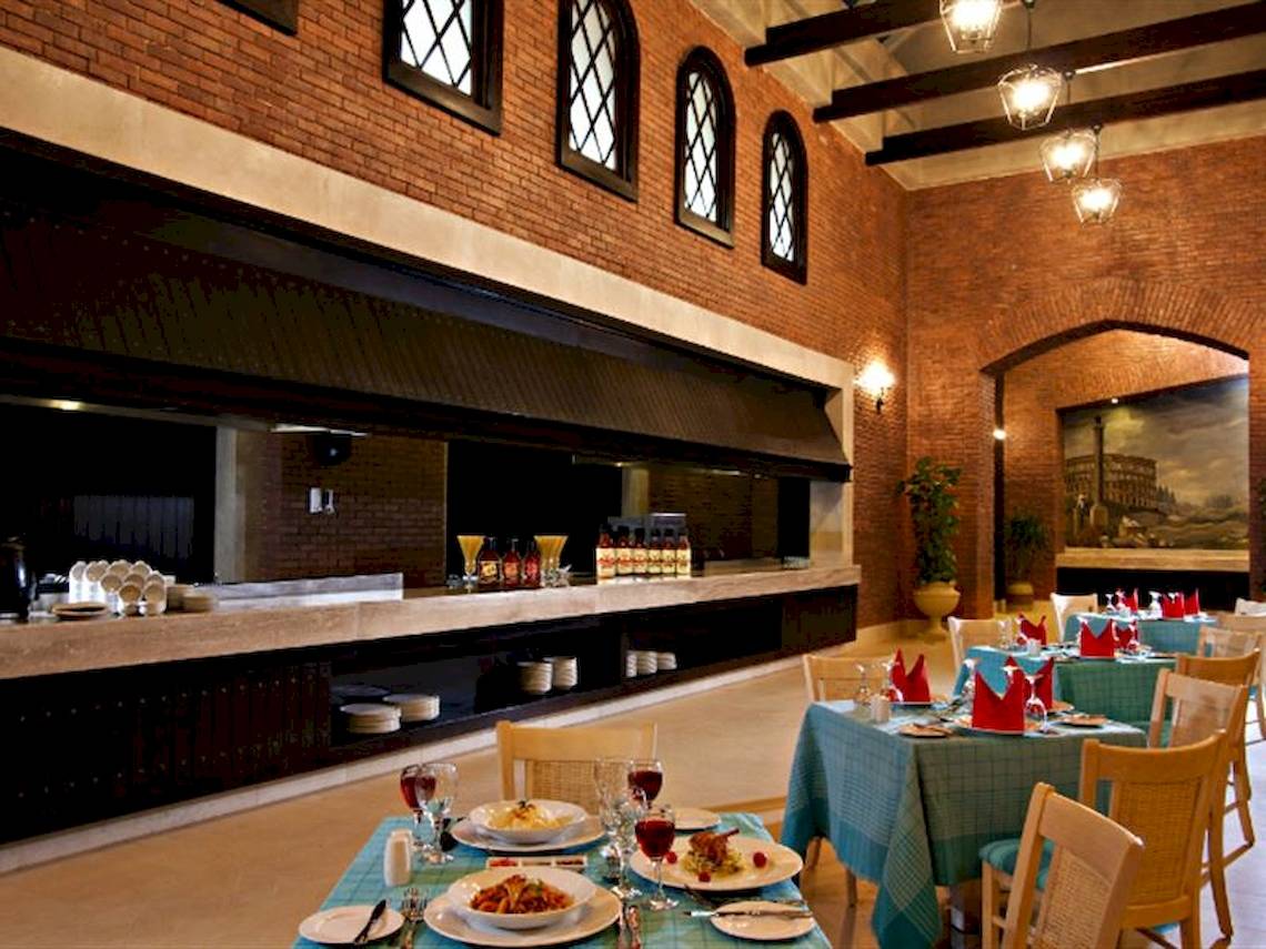 Innenansicht des Restaurants im Serenity Alma Heights Hotel mit Tisch und Stühlen, Geschirr und Dekoration.