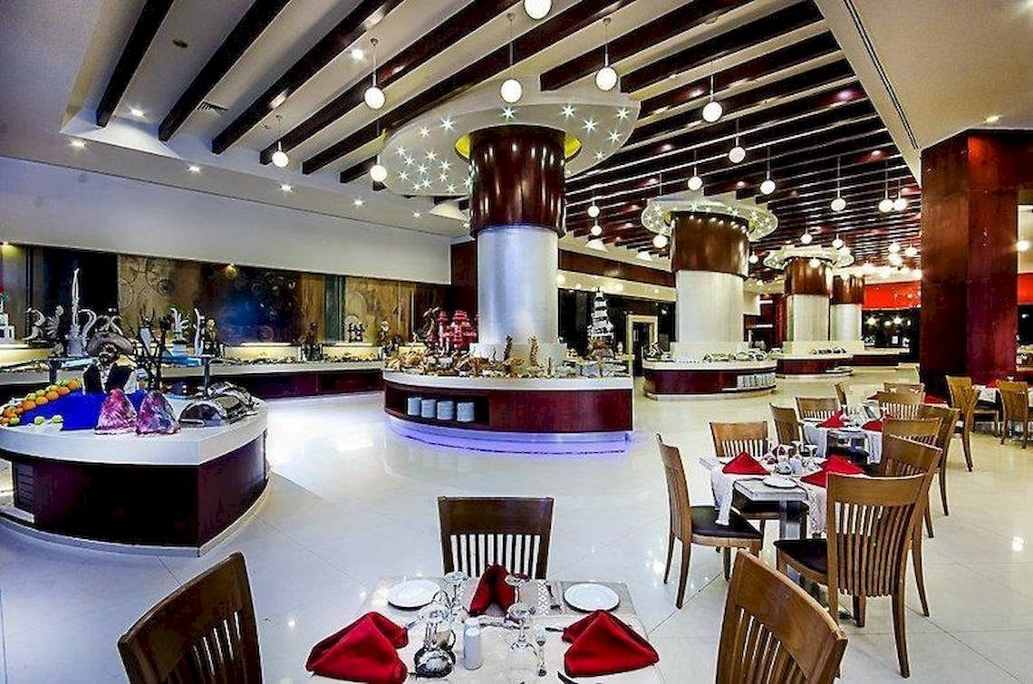 Innenansicht des Restaurants im Serenity Alma Heights Hotel mit gedeckten Tischen und Buffet.