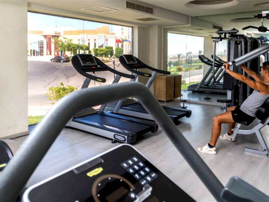 Fitness-Center im Serenity Alma Heights Hotel mit mehreren Laufbändern und einem Mann, der an einem Gerät trainiert.