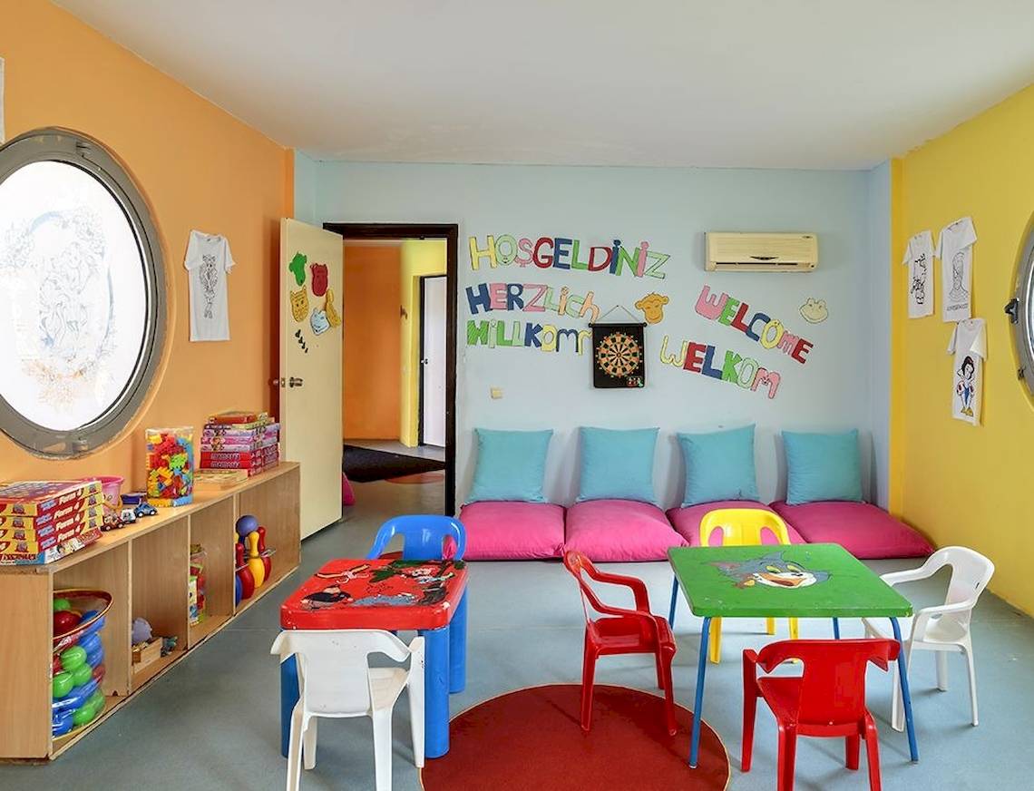 Kinder Spielzimmer im Sunis Elita Beach Resort Hotel & Spa mit bunten Wänden, Spieltischen und -stühlen.