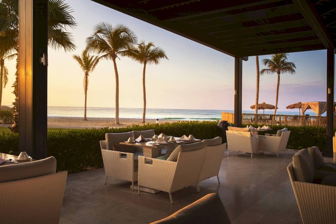 Terrasse des Salalah Rotana Resorts mit Blick auf einen Strand und Palmen