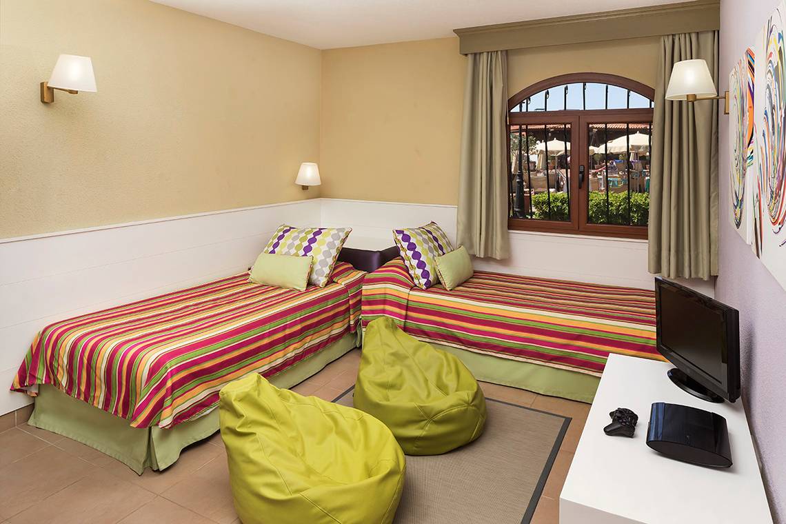 Hotelzimmer mit zwei Betten, Fernseher und Spielkonsole auf einem Tisch