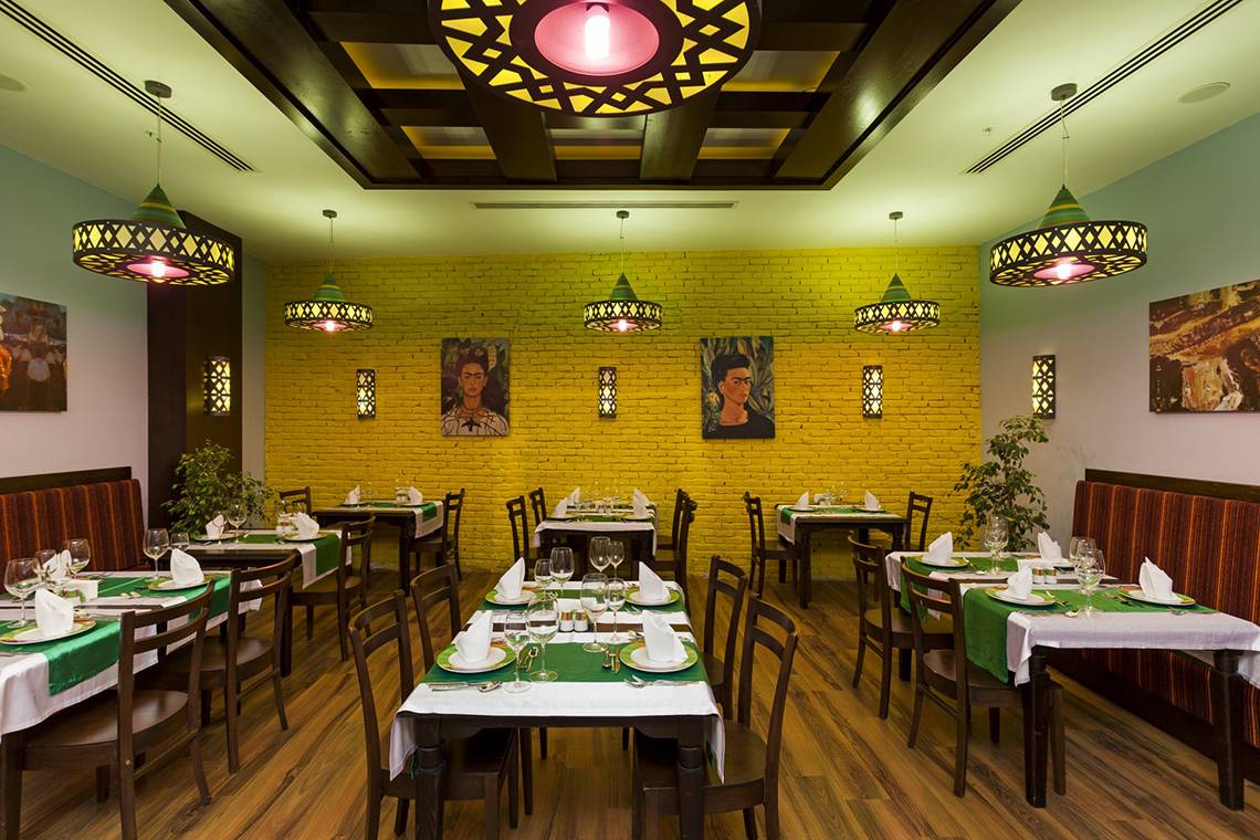 Innenansicht des Restaurants im Roma Beach Resort & Spa mit gelben Wänden und runden Kronleuchtern.