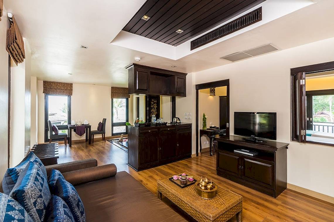 Wohnzimmer im Dara Samui Beach Resort mit Sofa, Fernseher und Esstisch.