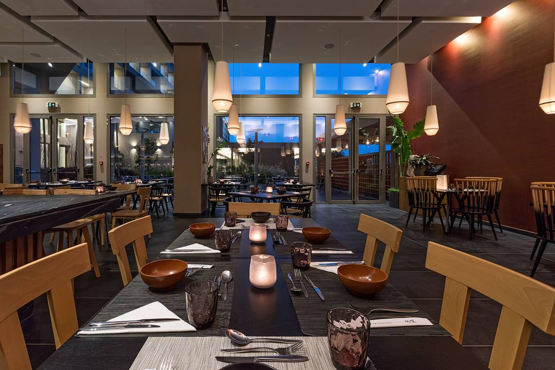Innenansicht des Restaurants im Amada Colossos Resort mit gedeckten Tischen und Blick auf den Garten.