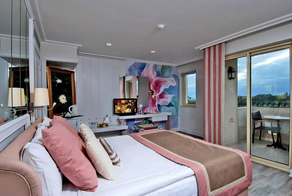 Zimmer im Delphin Diva Premiere Hotel mit Bett, Fernseher und Balkonzugang.